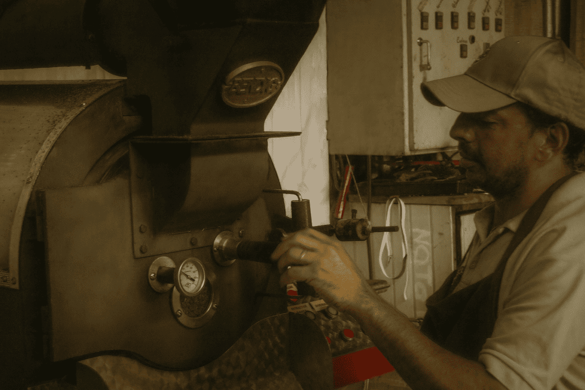 Mitarbeiter bedient einen traditionellen Trommelröster und zieht eine Bohnenprobe auf der Farm Granados (Café Granados) – frisch gerösteter Costa Rica Kaffee.