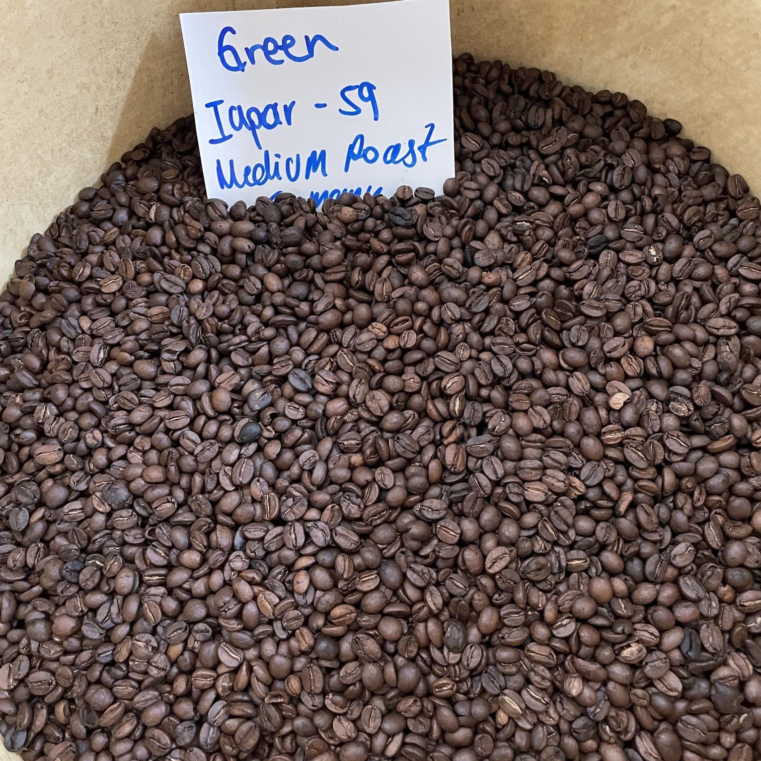 Geröstete Kaffeebohnen der Sorte Iapar 59 aus Costa Rica, beschriftet mit „Medium Roast“. Das Bild zeigt die frisch gerösteten Arabica-Bohnen mit ihrer glänzenden, dunklen Oberfläche.