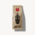 Kraftpapier-Kaffeebeutel mit rotem Geisha-Label und schwarzer Maskenillustration, Marke Café Granados – Costa Rica Kaffee, freigestellt auf hellem Hintergrund.