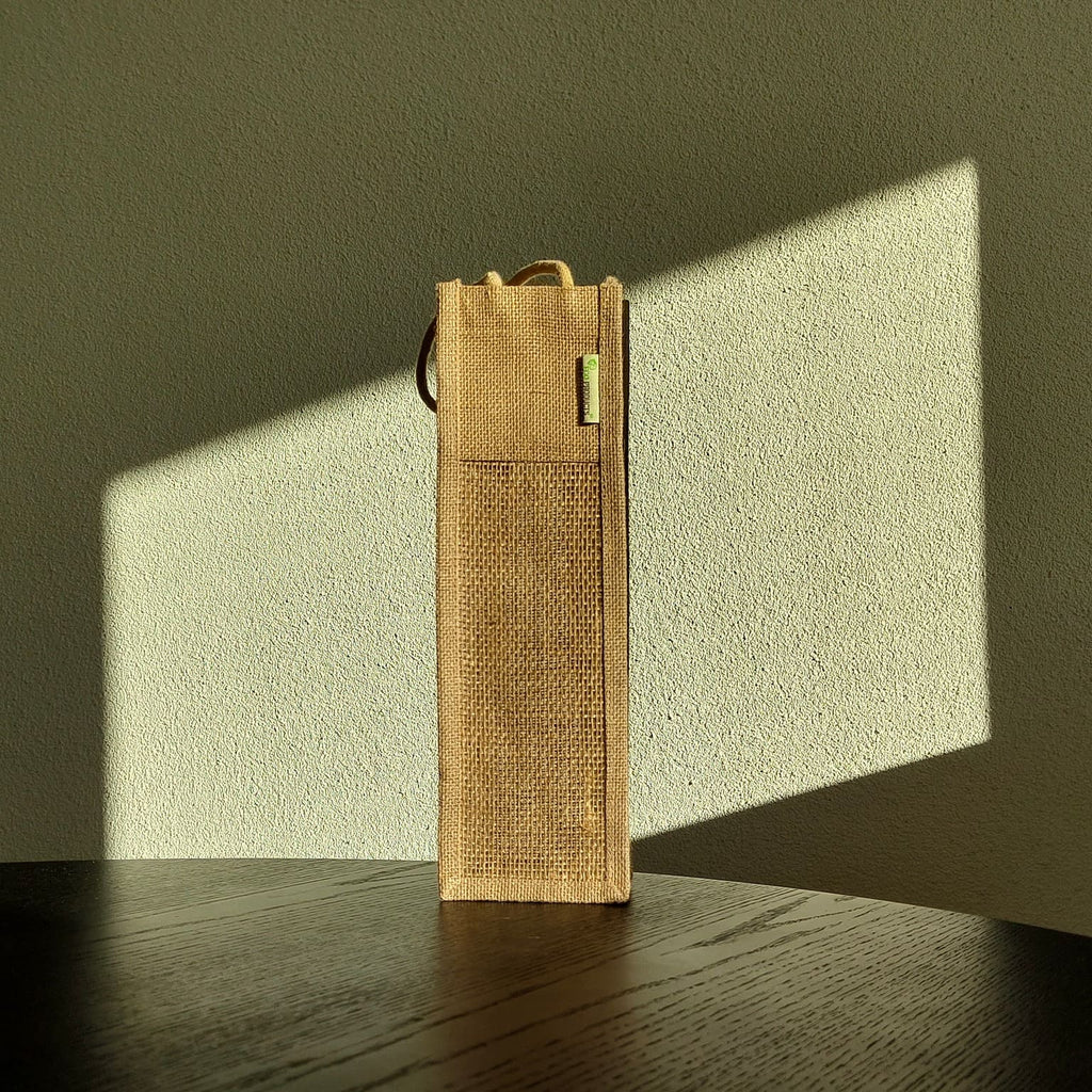 Seitenansicht einer Jute-Geschenkbox im Sonnenlicht vor Putzwand und Holzfläche – natürliche Verpackung für Costa Rica Kaffee von Café Granados.